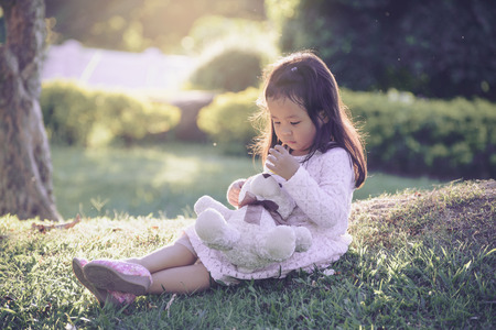 Cute  baby girl hugging soft bear toy, A young girl is playing with a stuffed animal teddy bear  sweet kid having fun outdoors in day careの写真素材