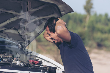 Stressed man  having trouble with his broken car ,looking in frustration at failed engine