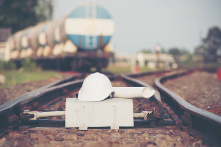 White helmet With the project plan  on the railroad tracks  with container trains on railways track in logistic station background.の写真素材