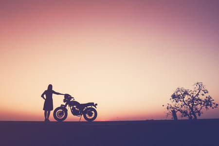Silhouette of classic motorcycle and a girl over sunset,freedom lifestyleの写真素材