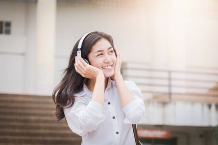 Asian girl student watching media content on smartphones and listening on line with wireless headphones,learn english, online education concept.の写真素材