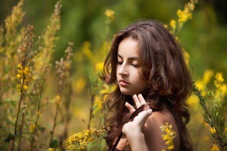 Portrait of a young woman on flowers field blured backgroundの写真素材