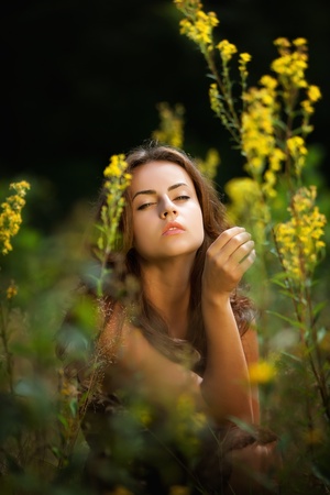 Soft portrait of a young woman on flowers field blured backgroundの写真素材
