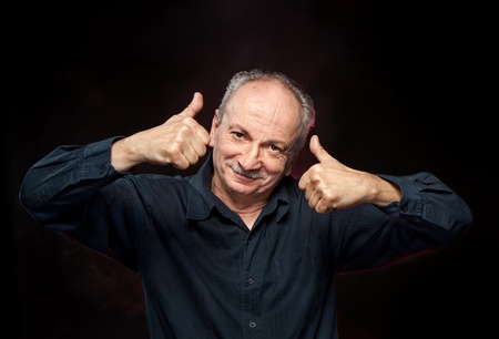 Successful man shows ok sigh on black backgroundの写真素材