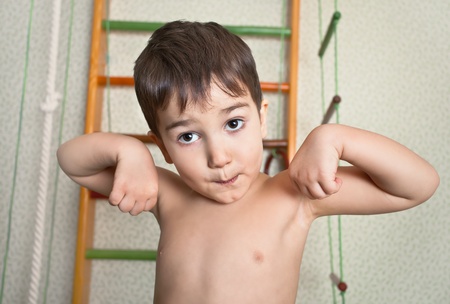 3 year old child at home sport gym shows muscles after a workoutの写真素材