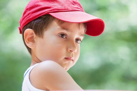 Portrait of a 3-4 years boy in a red cap on the blurred natural backgroundの写真素材