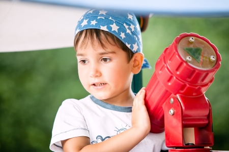 Little boy playing with a toy telescope at the playgroundの写真素材