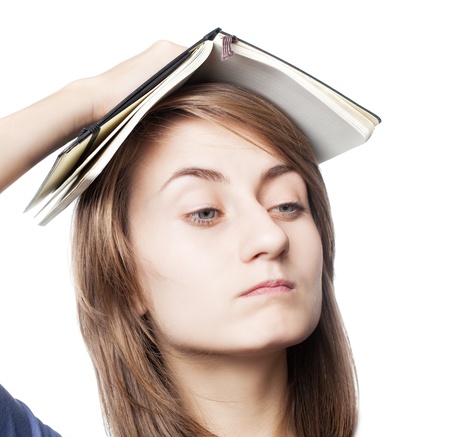 Education. Tired girl holds a notebook on her head on a white backgroundの写真素材