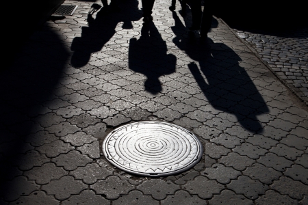 Shadows of people walking street in morning lightの写真素材