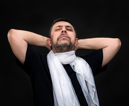 Portrait of a handsome man with a white scarf and closed eyes on a dark backgroundの写真素材
