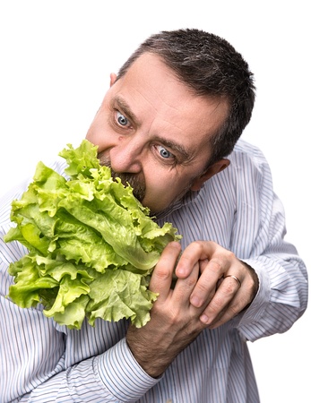 Healthy food. Man holding and eating lettuce isolated on whiteの写真素材