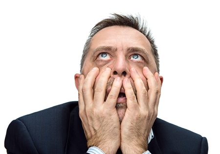 Fear and horror. Portrait of an middle age man with face closed by hands. Isolated on white
の写真素材