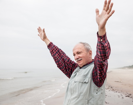 peaceful carefree older man with outstretched arms the coast at foggy dayの写真素材