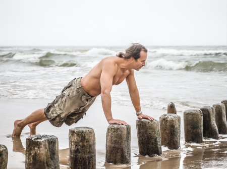 Middle-aged man doing pushups on the beachの写真素材