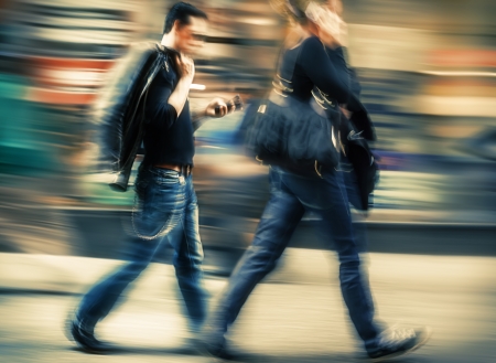 Hot day in the city. Man and woman talking on a cell phone in a hurry. Intentional motion blur and color shiftの写真素材