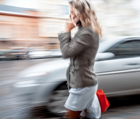 Abstract image of a young woman talking on a mobile phone on a city background with car. Intentional motion blurの写真素材