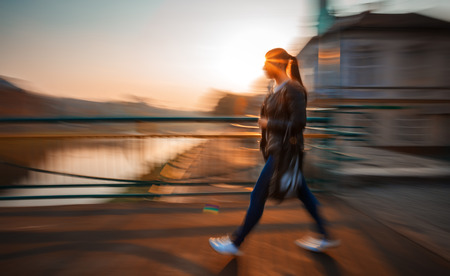 Abstract image of a woman walking down the street in morning sun light. Intentional motion blurの写真素材