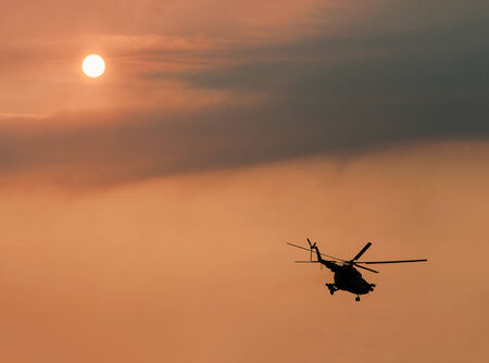 Ukrainian military helicopter in flight against a dramatic sunset after a combat missionの写真素材
