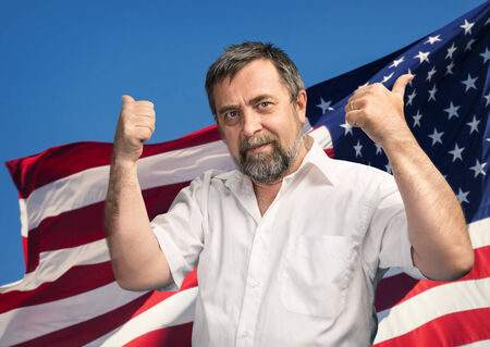 Patriotic concept. Man with thumbs up sign against United States of America flagの写真素材
