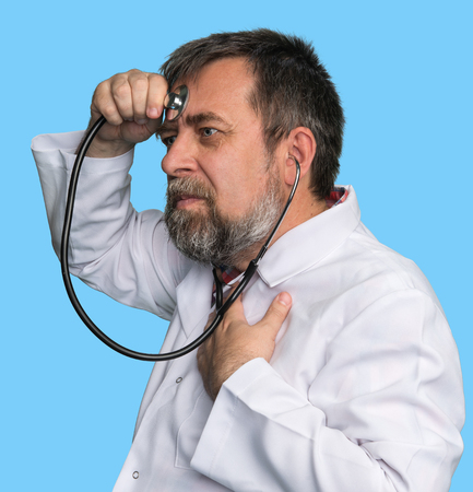 Humorous concept of health. Mad doctor with a stethoscope isolated on blue