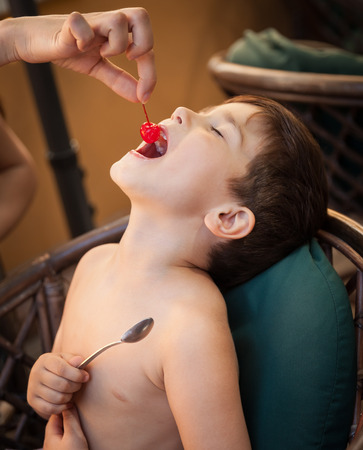 Portrait of 4-5 years old boy wants to eat a cherryの写真素材