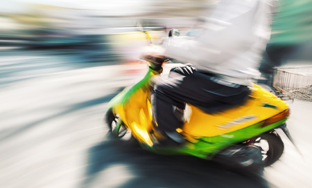 biker with a motorcycle in motion blur on city road in sunny dayの写真素材