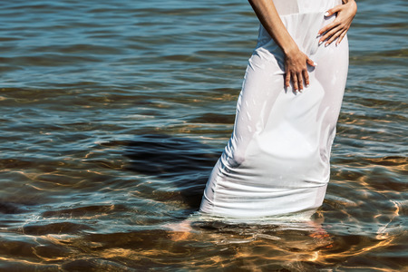 woman in wet white dress against the seaの写真素材