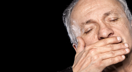 An elderly man with closed eyes closes and mouth isolated on black with copy-spaceの写真素材
