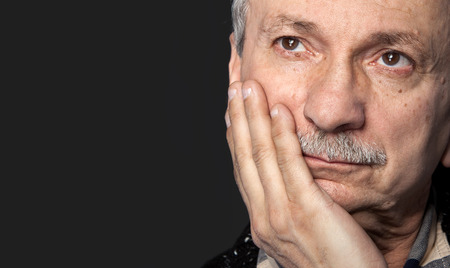 Portrait of handsome senior man with a tired expression on gray background with copy-space