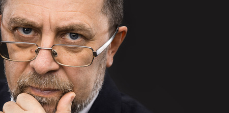 Portrait of handsome senior man with glasses prop up the head with his hand and copy-spaceの写真素材
