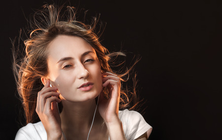 Beautiful Woman Listening Music on a dark background with copy-spaceの写真素材
