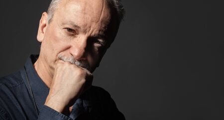 Portrait of handsome senior man on dark background with copy-spaceの写真素材