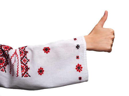 Hand of a young woman in the Ukrainian national clothes shows symbol ok with thumbs up isolated on white. Embroidered shirt.の写真素材