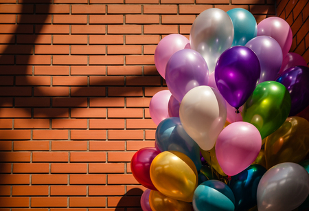 Bunch of colorful balloons against brick wall backgroundの写真素材