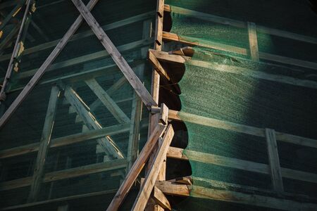 Building in the city. Wooden scaffolding and protective nettingの写真素材