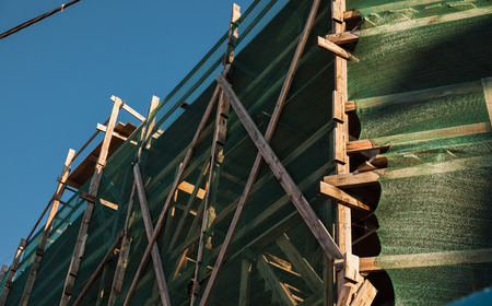 Building in the city. Wooden scaffolding and protective nettingの写真素材