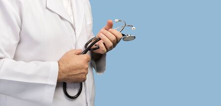 Close up image of a medical doctor with a stethoscope in his hands against blue background with copyspaceの写真素材