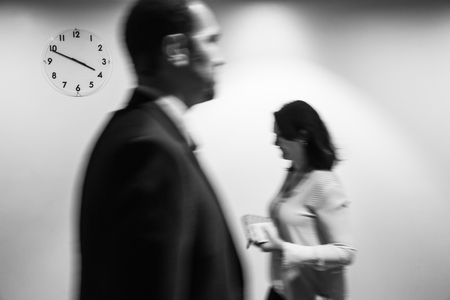 Passage of time concept. Blurred black and white image of people going about their business on the wall background with a clockのeditorial素材