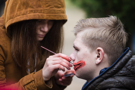 KIEV, UKRAINE - Oct 30, 2016: Zombie Walk. Young people taking part in a zombie parade in the streets of Kiev, to celebrate Halloween.Young man gets bloody makeupのeditorial素材