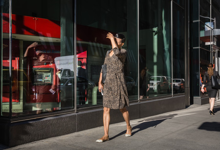 NEW YORK, USA - Sep 22, 2016: New York and New Yorkers. Manhattan street scene. The Americans on the streets of New York City. Woman go to work early morning and closes face by hand from the bright sunのeditorial素材