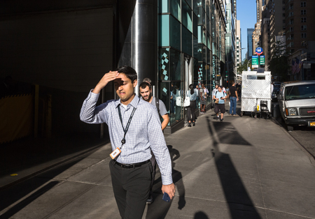 NEW YORK, USA - Sep 22, 2016: New York and New Yorkers. Manhattan street scene. Americans on the streets of New York City. Young woman go to work early morning and closes face by hand from bright sunのeditorial素材