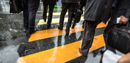 People cross street at crosswalk on a rainy day in the city. Intentional motion blurの写真素材