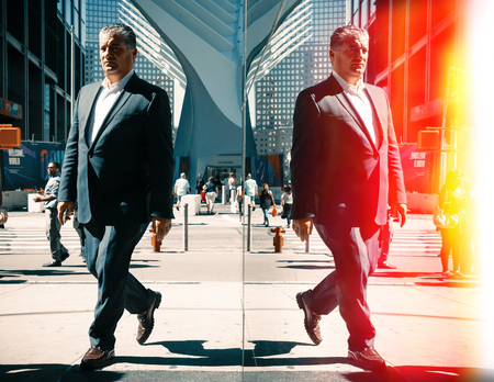 NEW YORK, USA - Sep 22, 2016: Manhattan reflections street scene. New York and New Yorkers. An elderly man in a suit on the streets of NYC. Film cross process stylizationのeditorial素材