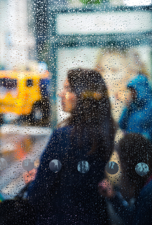 Rain in the city. Blurred scene of urban life. Emotional abstract background with defocused people and water drops on the streets of New York on a rainy dayの写真素材