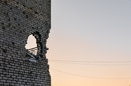 DONETSK REGION, UKRAINE - Dec 18, 2016: Destroyed houses and ruins, mechanisms, chaos and deserted village due to the war in eastern Ukraine. Hole in the wall of an artillery shellのeditorial素材