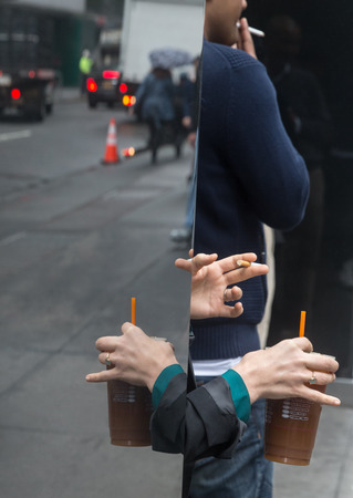 Coffee break in the streets of New York City. Womans hands with a cup of coffee and a cigarette and a man with cigaretteの写真素材