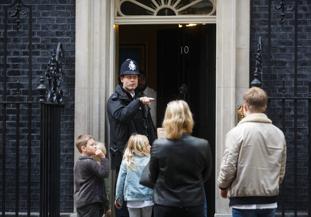 LONDON, UK - Apr 19, 2017: Metropolitan police officer on duty at 10 Downing Street communicates with a group of people on the doorstep of the prime minister's residence in the UKのeditorial素材