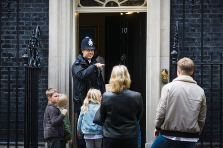 LONDON, UK - Apr 19, 2017: Metropolitan police officer on duty at 10 Downing Street communicates with a group of people on the doorstep of the prime minister's residence in the UKのeditorial素材