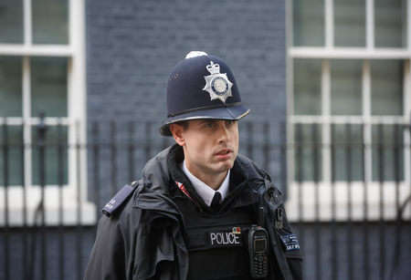 LONDON, UK - Apr 19, 2017: Metropolitan police officer on duty at 10 Downing Street official residence of First Lord of the Treasury, headquarters of Her Majesty's Government, office of Prime Ministerのeditorial素材
