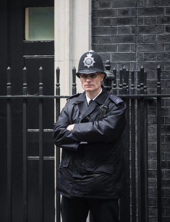 LONDON, UK - Apr 19, 2017: Metropolitan police officer on duty at 10 Downing Street official residence of First Lord of the Treasury, headquarters of Her Majesty's Government, office of Prime Ministerのeditorial素材